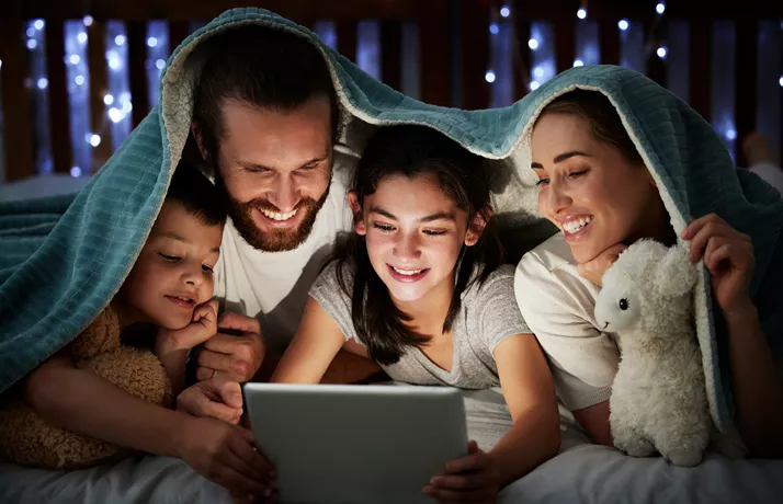 Family under blanket with ipad